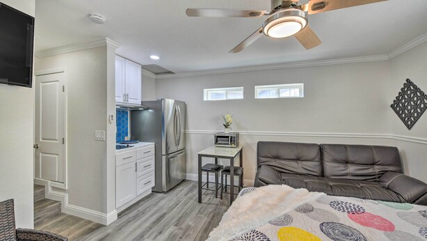 A bedroom with a bed, a ceiling fan, a kitchenette, and a dining area. - Cute Central Placerville Studio: Pet Friendly (Placerville)