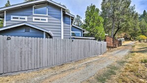 A residential property with a grey house, a wooden fence, and a gravel driveway. - Cute Central Placerville Studio: Pet Friendly (Placerville)