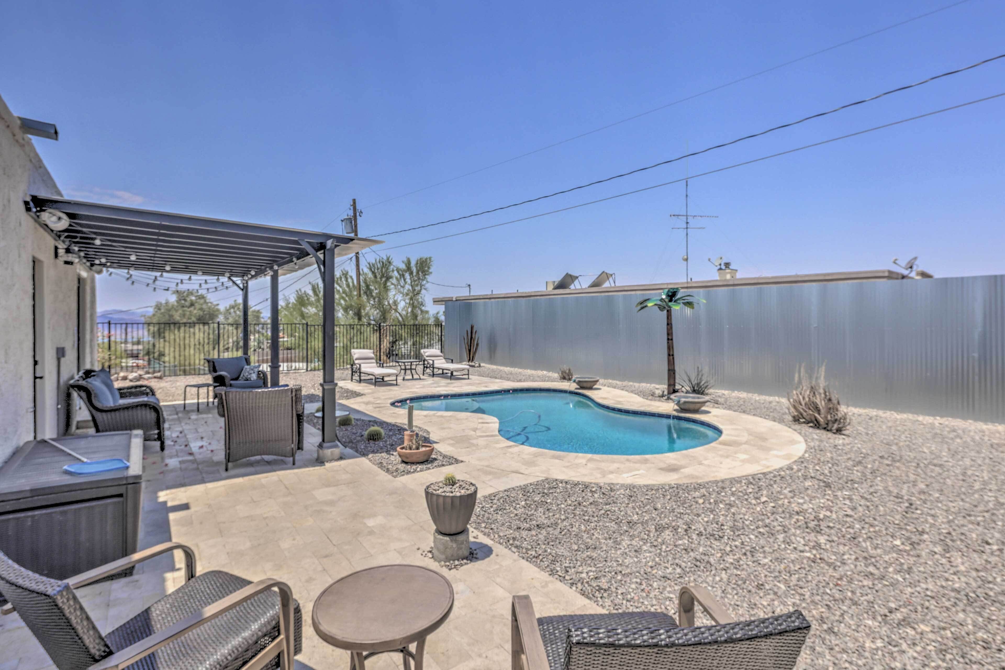 A backyard with a swimming pool, outdoor furniture, and a pergola.