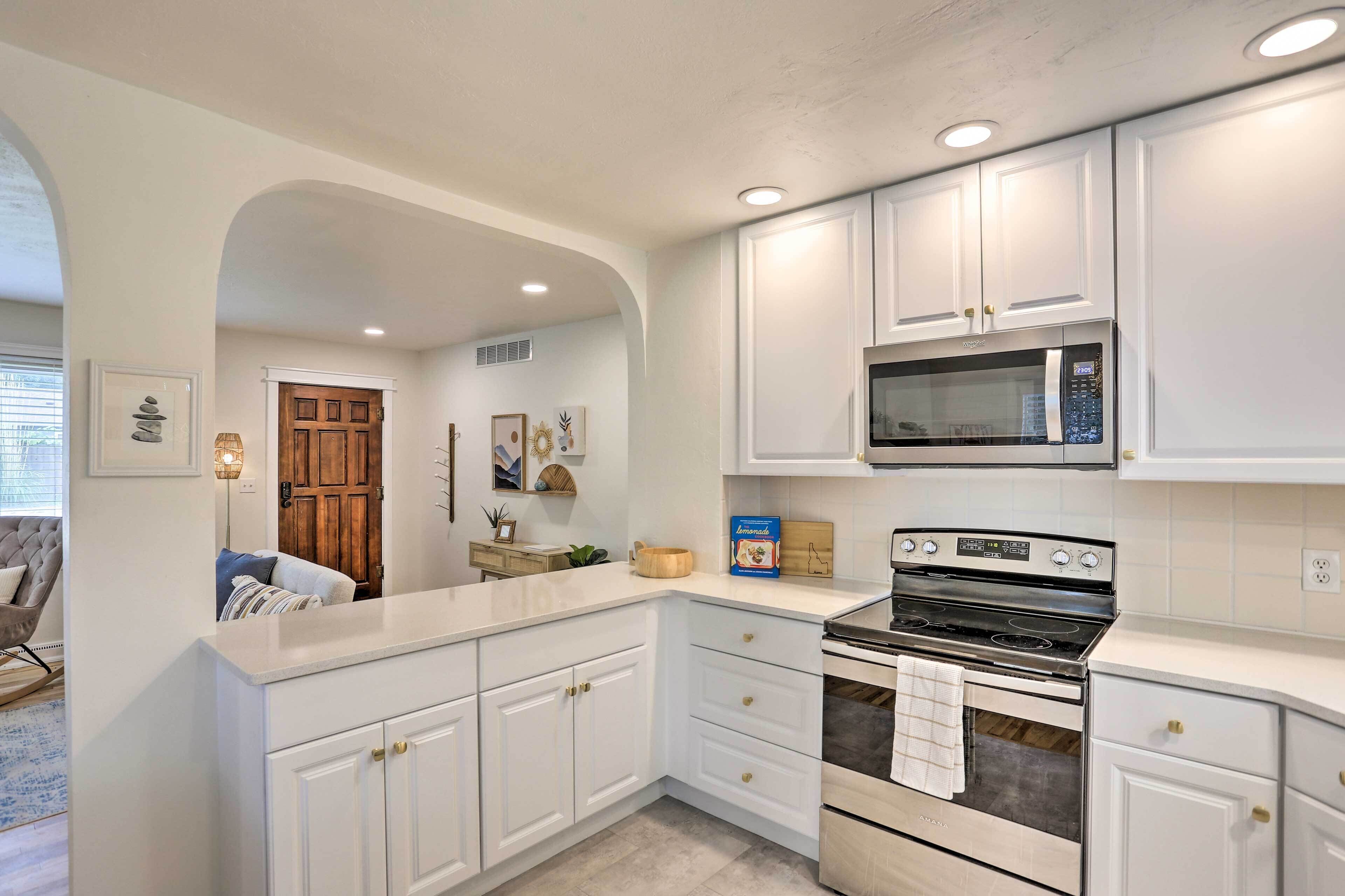 A kitchen with white cabinets, a microwave, and a stove.
