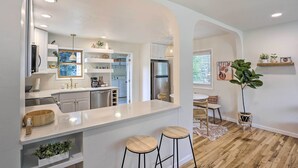 A modern kitchen with white cabinetry, stainless steel appliances, and a central island with stools. - Contemporary Boise House w/ Large Backyard! (Boise)
