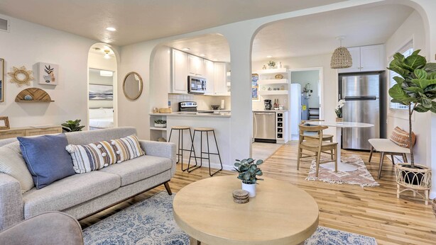 A modern living room with a sofa, coffee table, and a dining area with chairs and a table. - Contemporary Boise House w/ Large Backyard! (Boise)