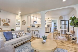 A modern living room with a sofa, coffee table, and a dining area with chairs and a table. - Contemporary Boise House w/ Large Backyard! (Boise)