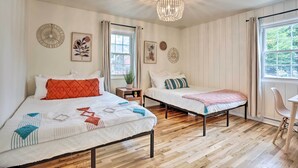 A bedroom with two beds, a chandelier, a window with curtains, and wall decorations. - Contemporary Boise House w/ Large Backyard! (Boise)