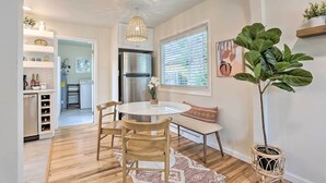 A modern kitchen with a round dining table, wooden chairs, a hanging light fixture, and a potted plant. - Contemporary Boise House w/ Large Backyard! (Boise)