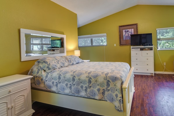 Une chambre à coucher avec un lit, une commode, un téléviseur et une fenêtre.
