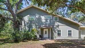 A two-story house with a front porch, a garage, and a small front yard. - St Petersburg Vacation Home 6 Mi to St Pete Beach! (St. Petersburg)