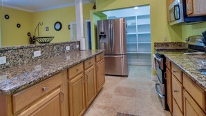 A kitchen with granite countertops, wooden cabinets, stainless steel appliances, and a microwave. - St Petersburg Vacation Home 6 Mi to St Pete Beach! (St. Petersburg)