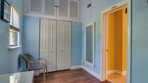 A room with a wooden floor, a white chair, a white table, and a door leading to a yellow room. - St Petersburg Vacation Home 6 Mi to St Pete Beach! (St. Petersburg)