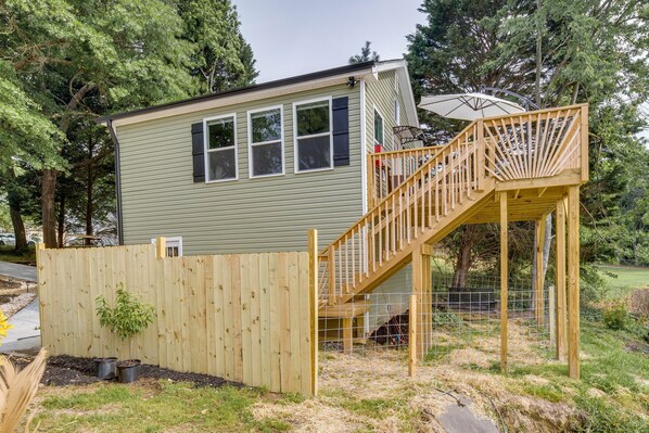 A small, single-story house with a wooden deck and a staircase leading to a covered porch.