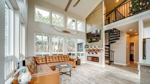 A spacious living room with a large sectional sofa, a fireplace, and a staircase leading to an upper level. - Hot Tub + Deck: Mtn-view Pine Getaway! (Pine)