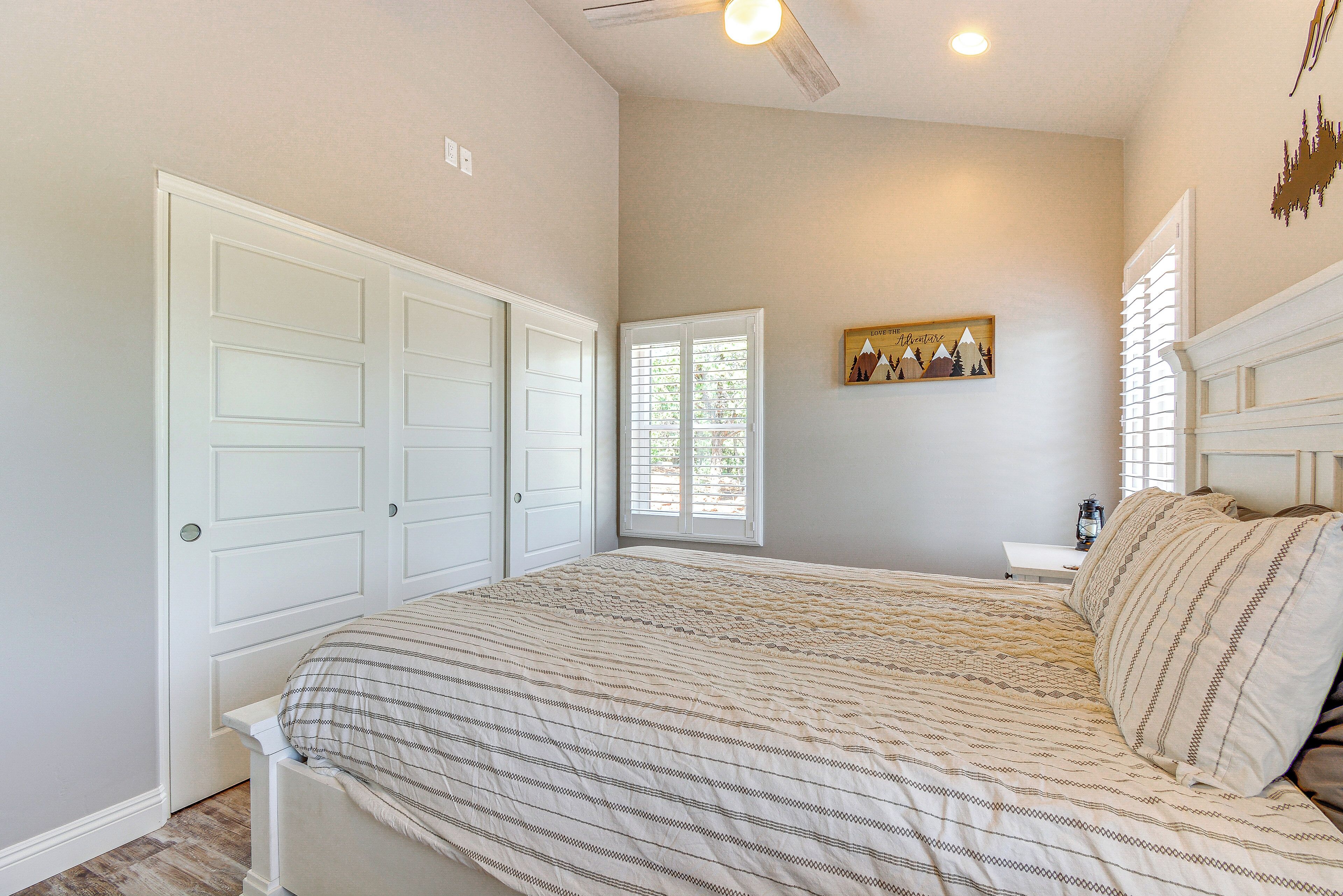 A bedroom with a bed, a window, a nightstand, and a wall-mounted picture.