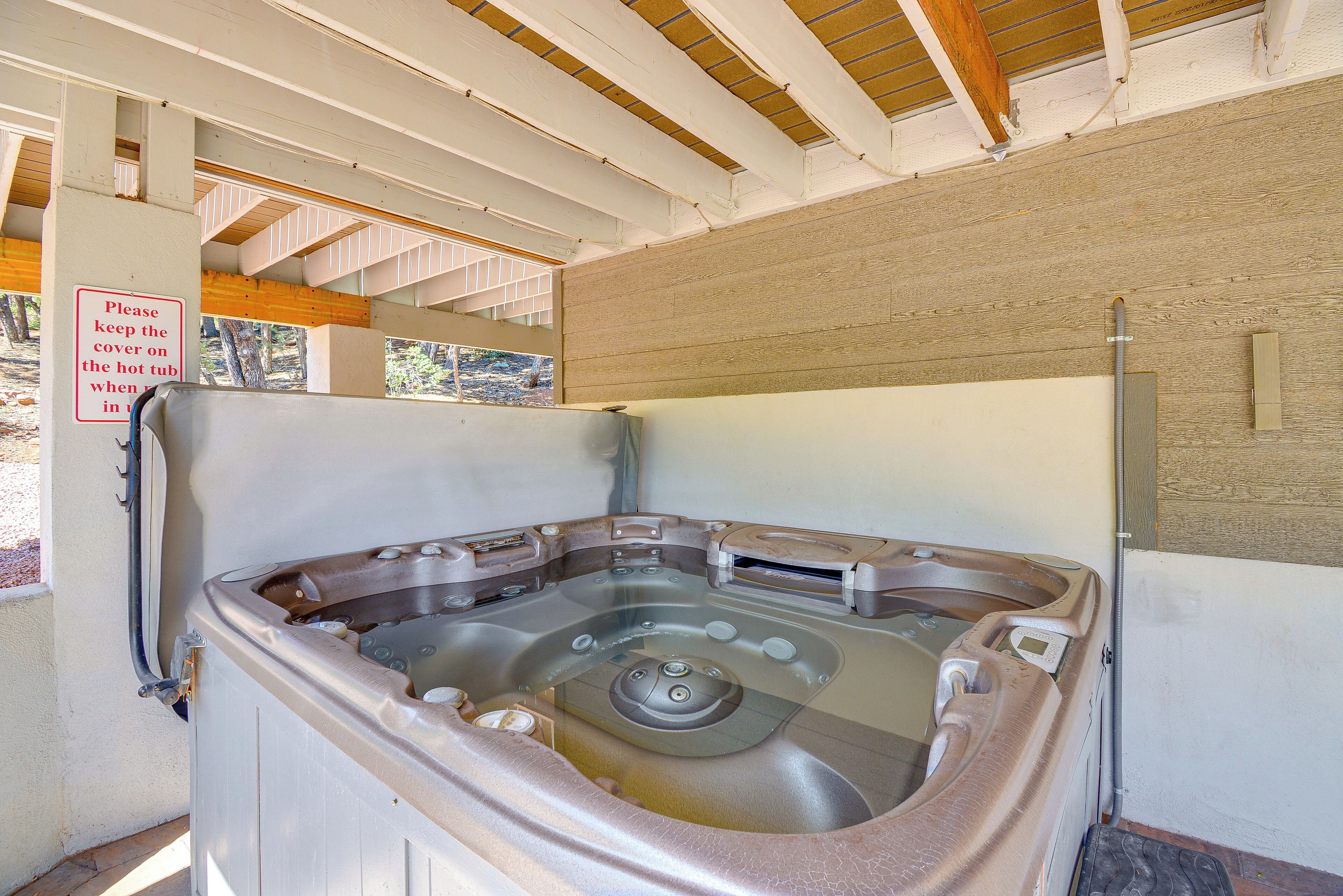 Una vasca idromassaggio con soffitto in legno e un cartello che invita a mantenere il coperchio quando non in uso.