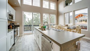 A spacious kitchen with a large island, white cabinetry, and a view of the outdoors through large windows. - Hot Tub + Deck: Mtn-view Pine Getaway! (Pine)