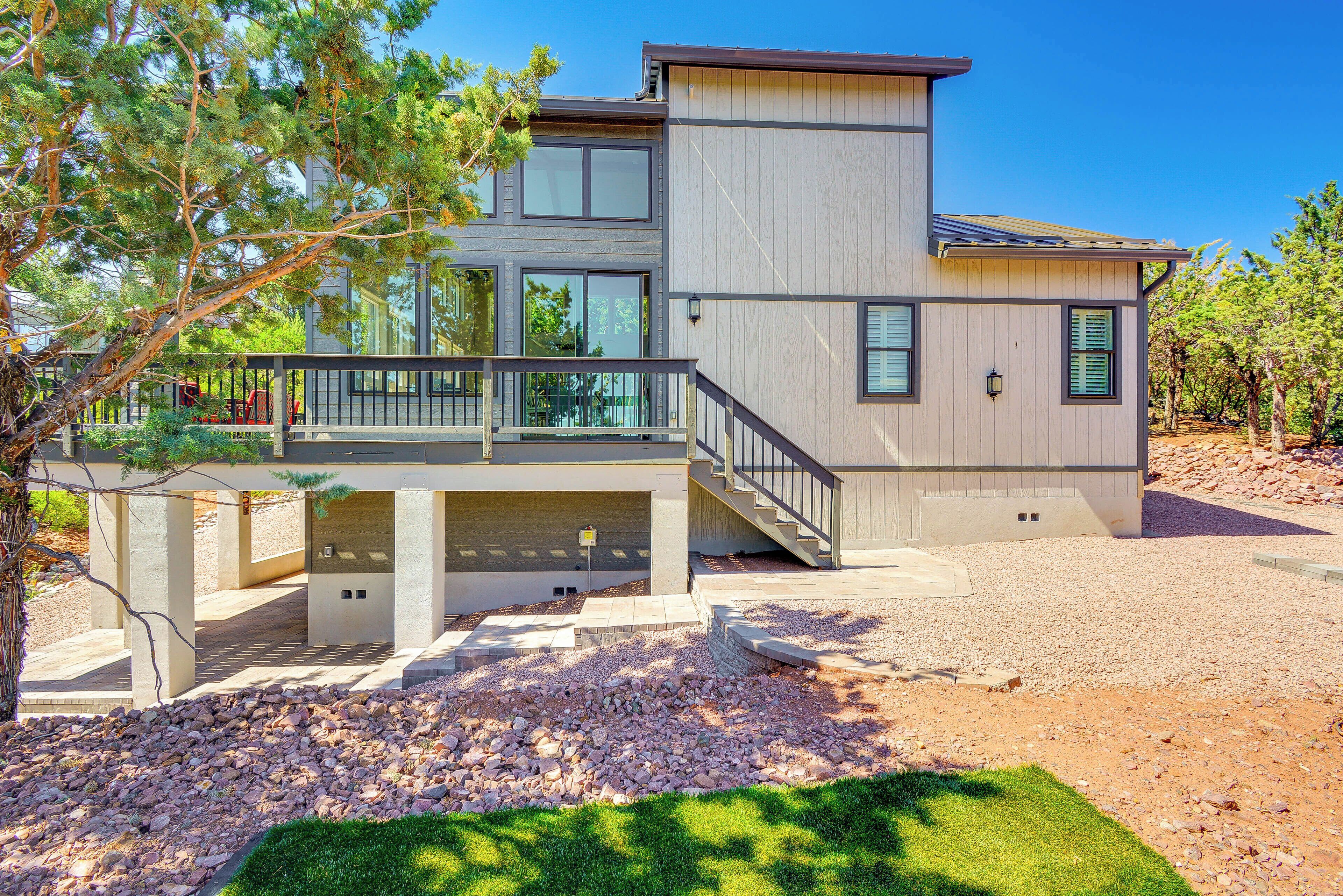 A modern two-story house with a covered patio, a staircase, and a well-maintained lawn.