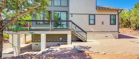 A modern two-story house with a covered patio, a staircase, and a well-maintained lawn.