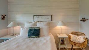 A neatly arranged bedroom with a bed, two bedside tables, a chair, and a wall-mounted shelf. - Rockport Condo ~ 6 Mi to Rockport Beach Park! (Rockport)