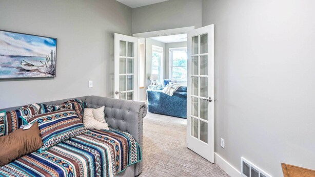 A room with a grey sofa, a patterned throw blanket, and a painting of a boat on the wall. - Waterfront Mound Retreat w/ Dock & Lake Access! (Mound)