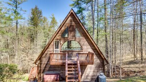 Une cabane en bois dotée d’un balcon, d’une échelle et d’un petit espace porche.
