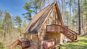 Une cabane en bois dotée d’un balcon, d’un escalier et d’une grande fenêtre.