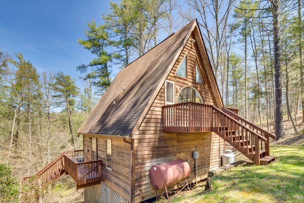 A wooden cabin with a balcony, a staircase, and a large window.