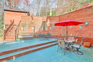 A wooden deck with a table and chairs, a red umbrella, and a staircase leading to a wooden building. - Asheville Mountain Getaway w/ Patio & Koi Pond! (Asheville)
