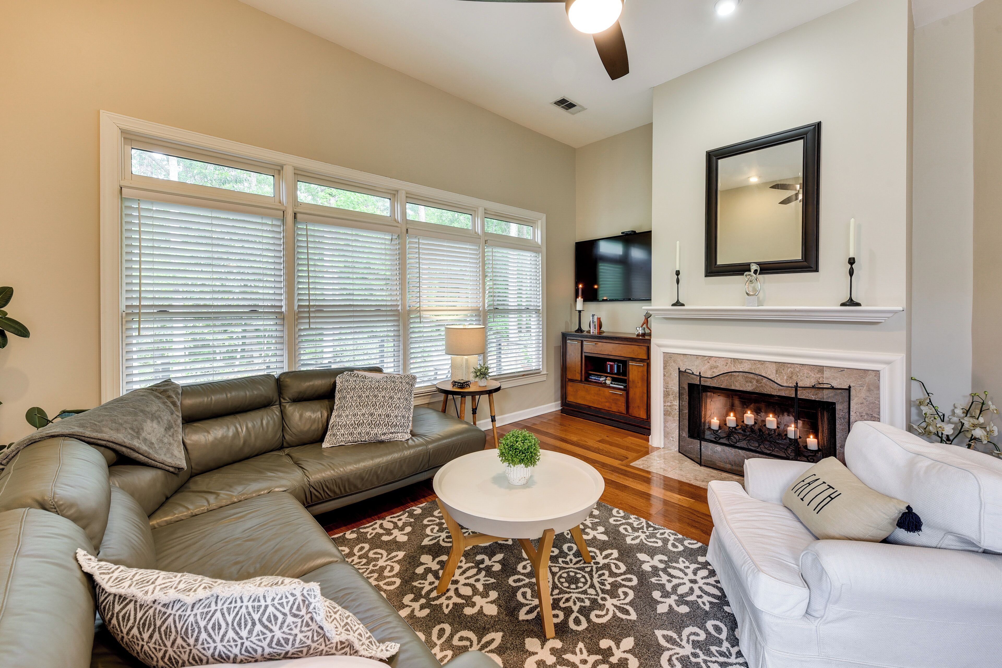 A living room with a sectional sofa, a white armchair, a round coffee table, and a fireplace.