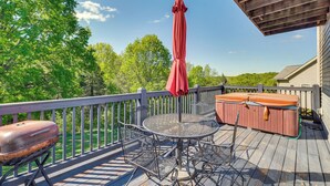 A wooden deck with a metal table and chairs, a red umbrella, and a hot tub. - Taylorsville Lake Cottage Rental w/ Hot Tub! (Taylorsville)