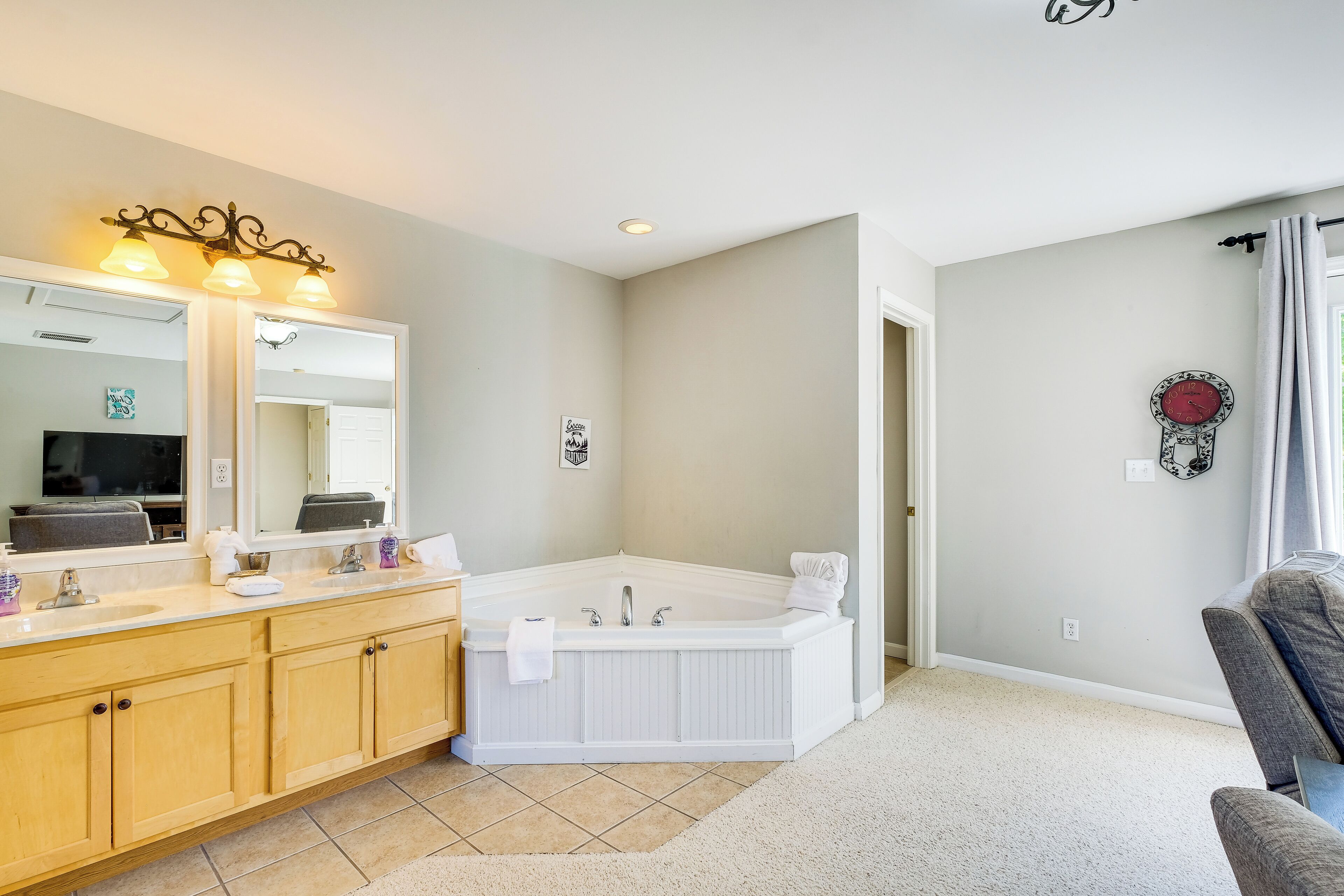 A modern bathroom with a large mirror, two sinks, a freestanding bathtub, and a vanity with cabinets.
