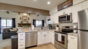 A modern kitchen with white cabinets, stainless steel appliances, and a stone fireplace. - Forest-view Balcony: Pinetop-lakeside Condo (Pinetop)