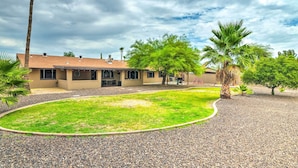 A building with a curved driveway, a lawn, and palm trees. - Modern Glendale Desert Destination w/ Patio! (Glendale)