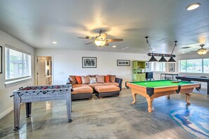 A spacious living area with a foosball table, pool table, and a sectional sofa. - Modern Glendale Desert Destination w/ Patio! (Glendale)