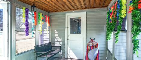A covered porch with a bench, a door, and colorful decorations.