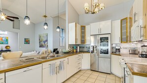 A modern kitchen with white cabinets, stainless steel appliances, and a wooden countertop.