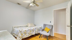 A bedroom with a single bed, a chair, a table, and a door.