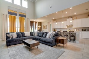 A spacious living room with a sectional sofa, a coffee table, and a kitchen area with white cabinets and bar stools. - Spacious San Antonio Home: 4 Mi to Seaworld! (San Antonio)