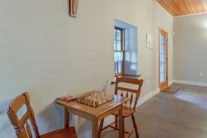 Een kamer met een houten tafel gedekt voor een spel, twee houten stoelen, een deur en een raam.