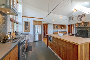 A modern kitchen with a central island, stainless steel appliances, wooden cabinetry, and pendant lighting. - Peaceful Marlboro Vacation Rental w/ Sauna & Yard! (Wilmington)