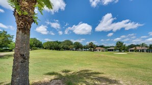 Un parcours de golf avec un palmier, de vastes espaces couverts d’herbe et un ciel bleu dégagé.