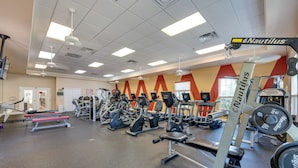 Une salle de sport équipée d’appareils Nautilus, de machines de cardio et de postes d’entraînement en musculation.