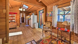 A wooden cabin interior with a kitchen, dining area, and a cozy living space.