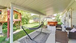 Un patio techado con mobiliario de mimbre, una hamaca y una casita de juegos de madera.