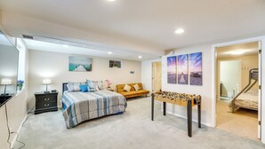 Un dormitorio con cama, sofá, mesa de fútbol y escritorio con lámpara.