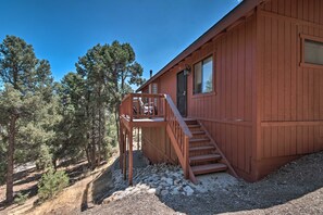 A wooden cabin with a wooden staircase leading to a deck, surrounded by trees. - Cozy Pine Mountain Cabin: Hike, Bike, Fish Nearby! (Pine Mountain Club)