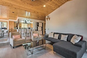 A modern living room with a glass coffee table, two armchairs, a sofa, and a kitchen in the background. - Cozy Pine Mountain Cabin: Hike, Bike, Fish Nearby! (Pine Mountain Club)