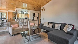 A modern living room with a glass coffee table, two armchairs, a sofa, and a kitchen in the background. - Cozy Pine Mountain Cabin: Hike, Bike, Fish Nearby! (Pine Mountain Club)