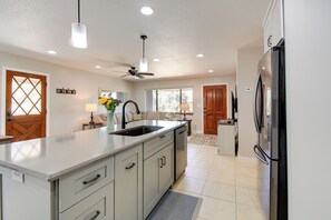 A modern kitchen with a large island, a refrigerator, and a ceiling fan. - Putting Green & Patio: Central Prescott Home (Prescott)