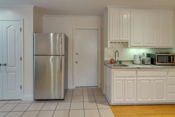A kitchen with white cabinets, a stainless steel refrigerator, a microwave, and a toaster. - Gulf Breeze Vacation Rental for 2 w/ Pool Access! (Gulf Breeze)