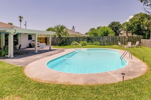 En baghave med swimmingpool, overdækket terrasse og træhegn.
