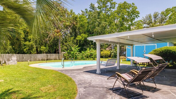 A backyard with a swimming pool, covered patio, and outdoor furniture. - Gulf Breeze Vacation Rental for 2 w/ Pool Access! (Gulf Breeze)